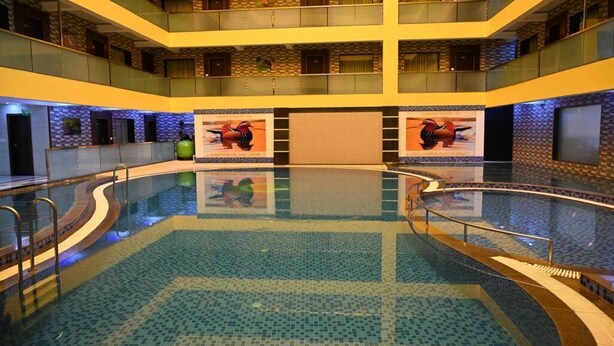 Une piscine intérieure à plusieurs niveaux, dotée d’une eau claire, entourée d’un sol et de murs carrelés, et agrémentée de balcons à chaque niveau.