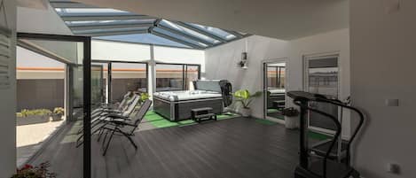 A modern interior with a glass ceiling, a sofa, a treadmill, and a view of the outside.