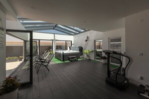 A modern interior with a glass ceiling, a sofa, a treadmill, and a view of the outside. - Casa Amável - Vila Serena (Caldas da Rainha)