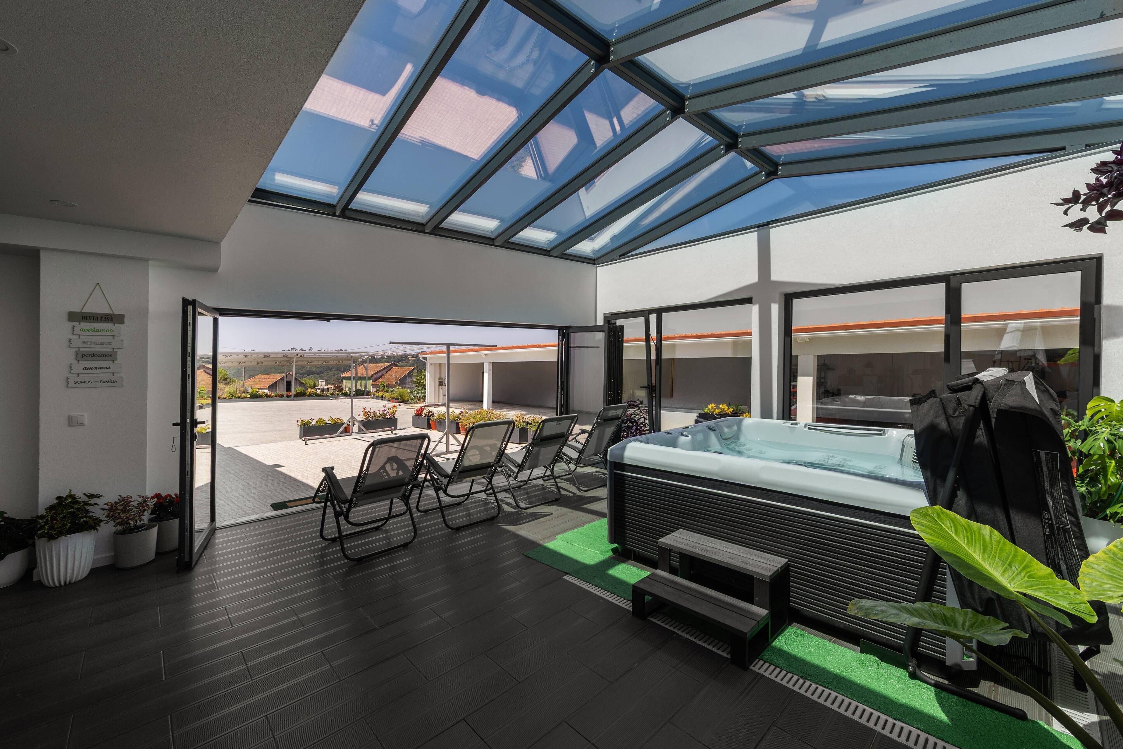 Un patio intérieur moderne doté d’un toit en verre, d’un jacuzzi, d’un espace salon et de plantes en pot.