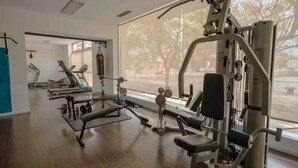 A gym with various exercise equipment, large windows, and a wooden floor. - Elegante departamento frente al Dique (Buenos Aires)