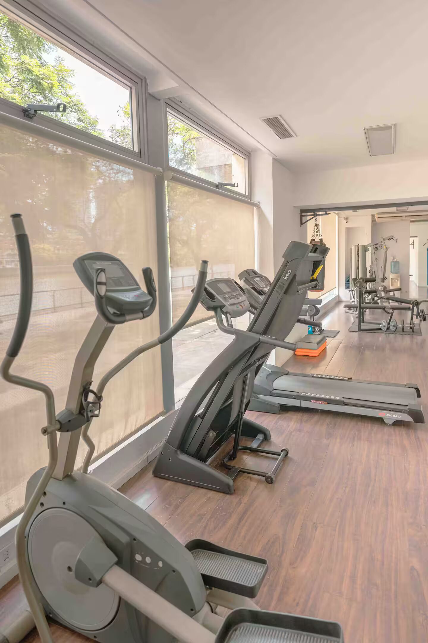 Une salle de sport équipée de nombreux appareils d’exercice, dotée de grandes fenêtres et offrant une vue sur l’extérieur.