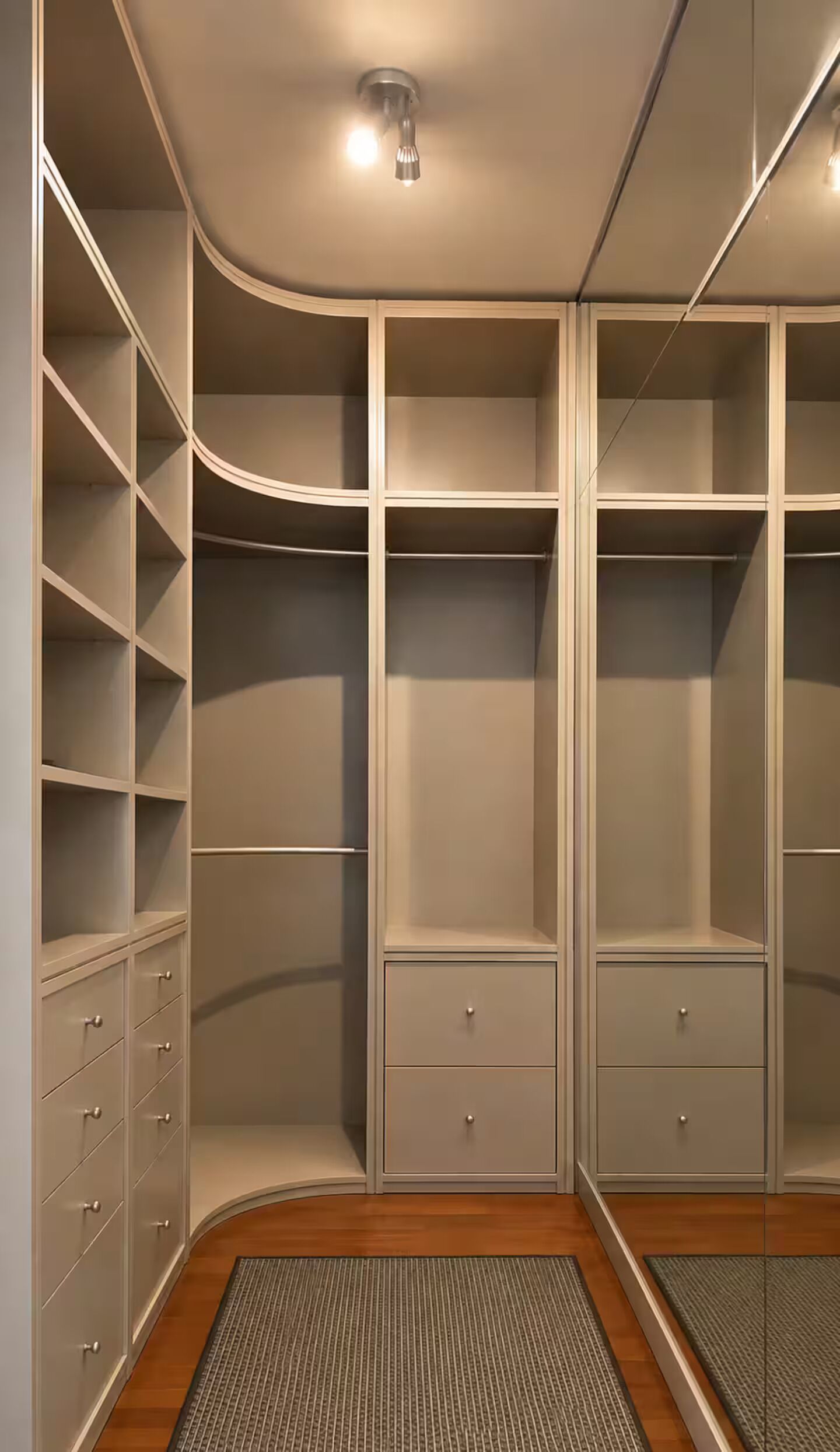 Ein begehbarer Kleiderschrank mit offenen Regalen, Schubladen und einer spiegelnden Schiebetür.
