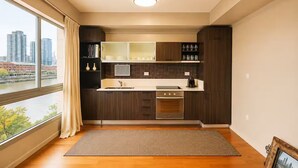 A modern kitchen with a large window, wooden cabinets, and a built-in oven. - Elegante departamento frente al Dique (Buenos Aires)