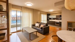 A modern living room with a sofa, coffee table, and dining table. - Elegante departamento frente al Dique (Buenos Aires)