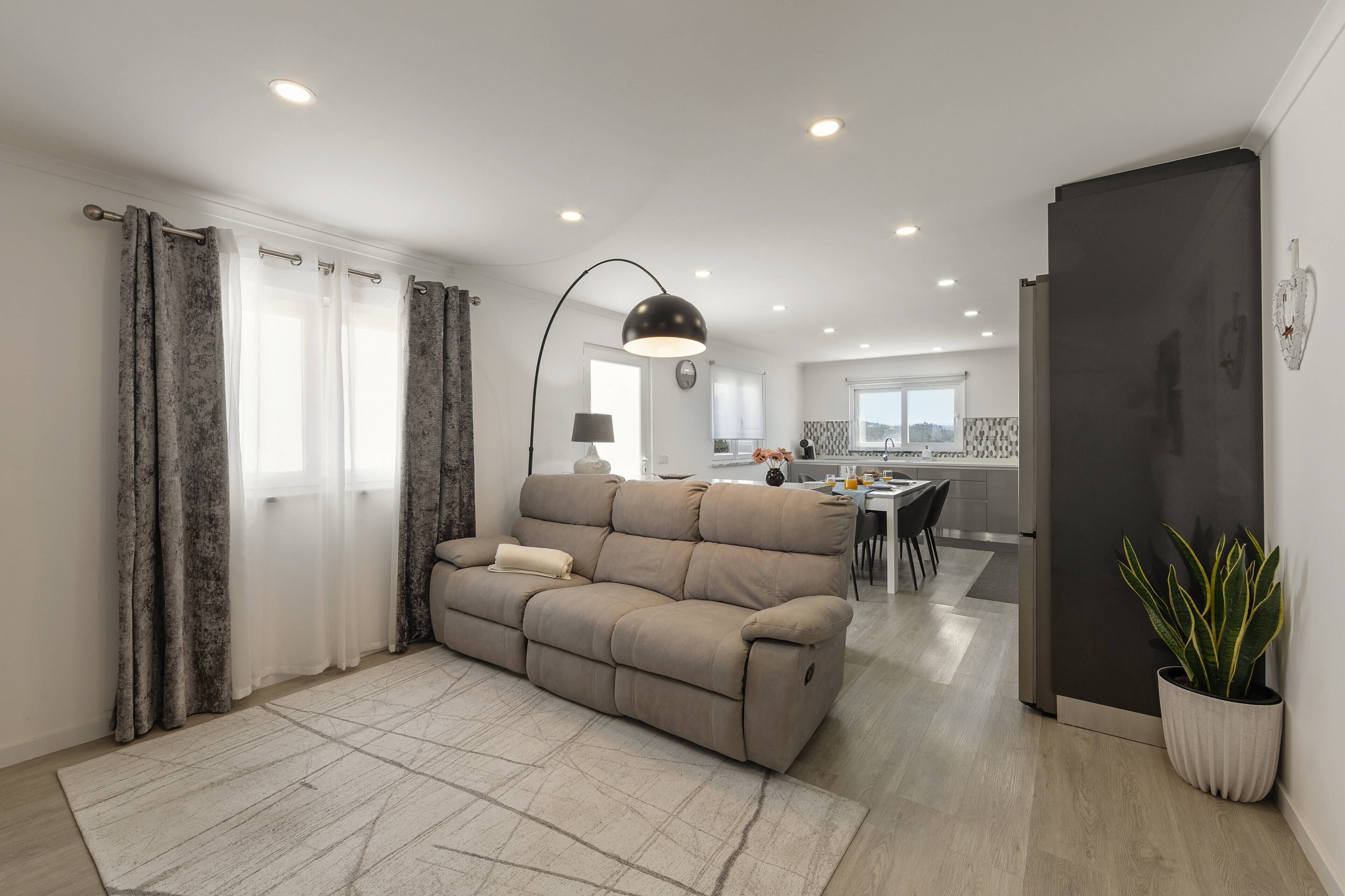 Ein modernes Wohnzimmer mit einer Couch, einem Essbereich und einer Küche im Hintergrund.