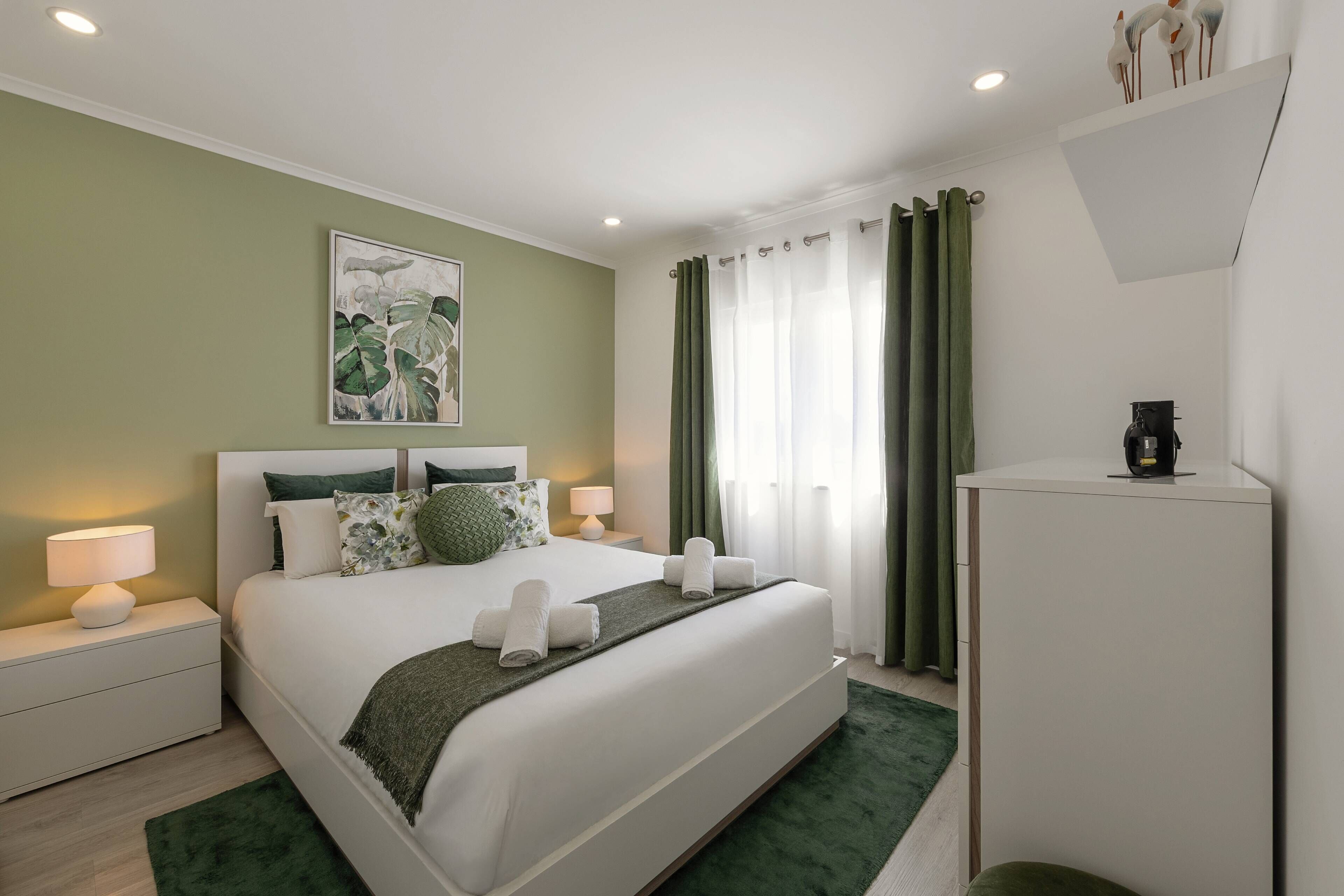 Une chambre d’hôtel moderne avec un grand lit, une table de chevet avec une lampe, un tableau au mur et une machine à café.