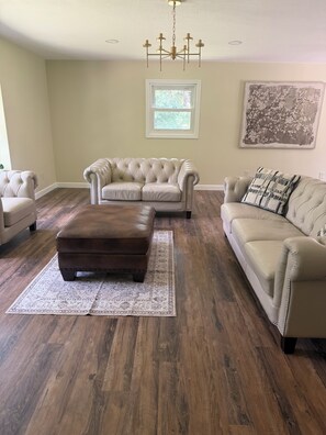 A living room with a sectional sofa, an ottoman, and a patterned rug. - Forest healing, rest and relaxation await surrounded by acres of forest & lakes. (Sturgis)