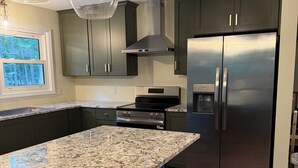 Una cucina moderna con un piano di lavoro in granito, elettrodomestici in acciaio inox e mobili scuri.