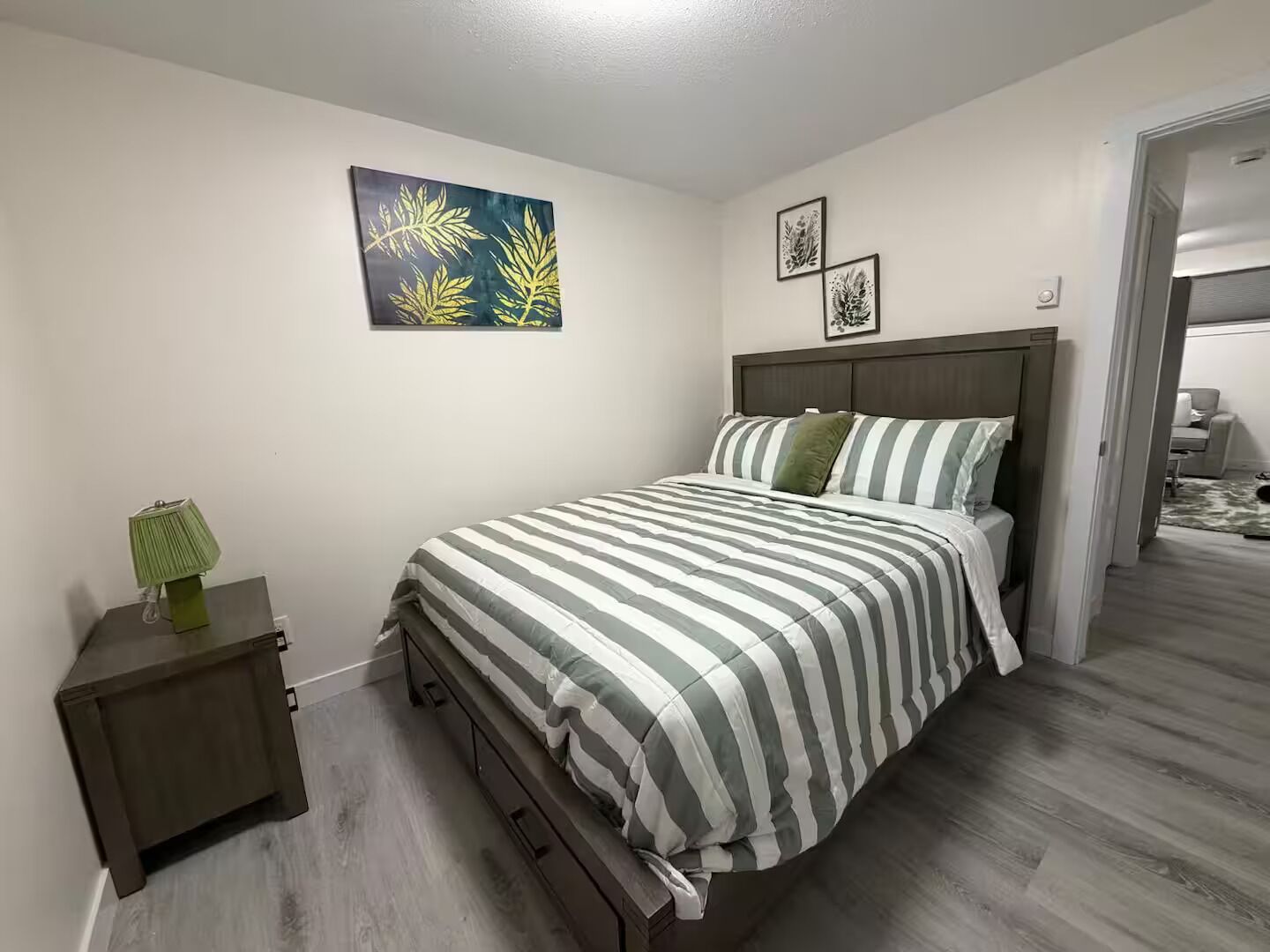 Un dormitorio con cama, mesita de noche y una pared decorada con obras de arte.
