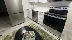 A modern kitchen with stainless steel appliances, including a refrigerator, dishwasher, microwave, and oven.