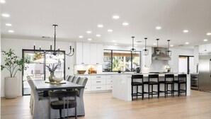 Uma cozinha moderna com ilha central, banquetas e iluminação pendente.