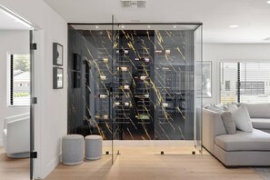 Ein modernes Wohnzimmer mit Glastrennwand, einem grauen Sofa und einem Weinkühlschrank.