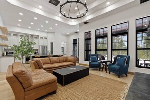 A modern living room with a leather sofa, a coffee table, and two armchairs. - Huckleberry Peak Villa -Glacies Montana-Game Room (Hungry Horse)