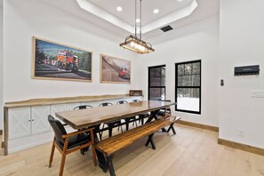 A dining area with a wooden table and benches, a hanging light fixture, and two framed pictures on the wall. - Huckleberry Peak Villa -Glacies Montana-Game Room (Hungry Horse)