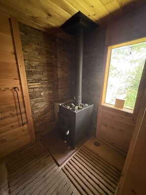 Ein Zimmer mit Kaminofen, Fenster und Holzboden.