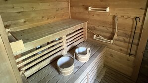 Un sauna de madera con bancos y dos cuencos de madera.