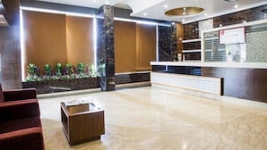 A hotel lobby with a reception desk, seating area, and a decorative plant wall. - Shri Ram Empire (Jodhpur)