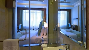 A hotel bathroom with a glass shower enclosure, a sink, and a large mirror reflecting the room. - Shri Ram Empire (Jodhpur)