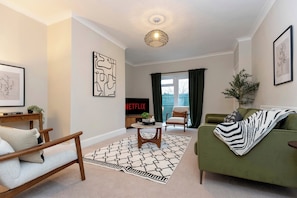 A living room with a sofa, a chair, a coffee table, a TV, and a decorative wall piece. - Gateshead 3BR Stay | Modern & Contractor Friendly (Ryton)