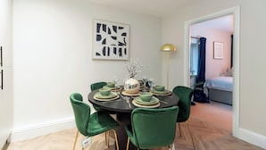 Un coin repas avec une table ronde, des chaises vertes et une lampe moderne.