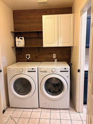A laundry room with two white LG front-loading washing machines, a wooden wall, and a white cabinet above. - 3-bedroom townhome in tranquil Northglenn, 25 minutes from Denver (Northglenn)
