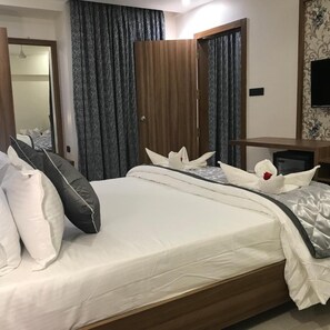 Habitación de hotel con cama, cortinas, armario de madera y televisor.