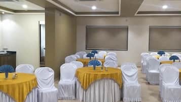 A conference room with round tables, white chairs, and yellow tablecloths.