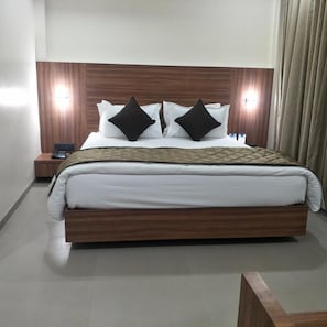 Una habitación de hotel con una cama, dos lámparas de noche, una mesita de noche y un cabecero de madera.