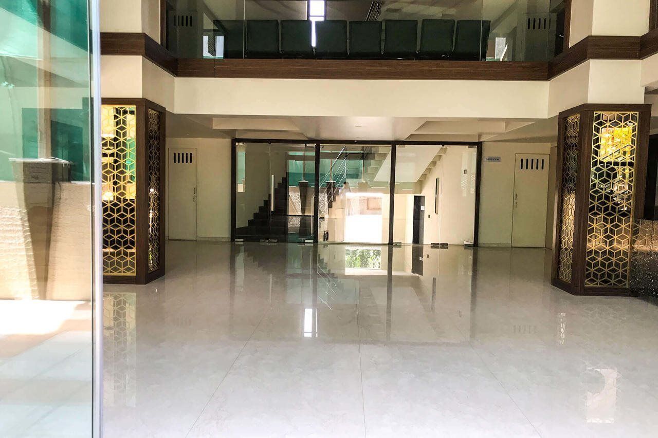 A spacious lobby with a glass door entrance, a staircase, and a modern design with geometric patterns on the walls.