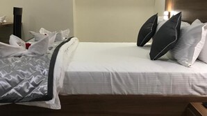 Una cama bien hecha con una manta de color gris y blanco con estampado, almohadas blancas y un cabecero de madera.