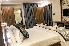 Una habitación de hotel con cama, escritorio, televisor y armario.