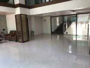 A spacious lobby with a high ceiling, a staircase, and a seating area with chairs.