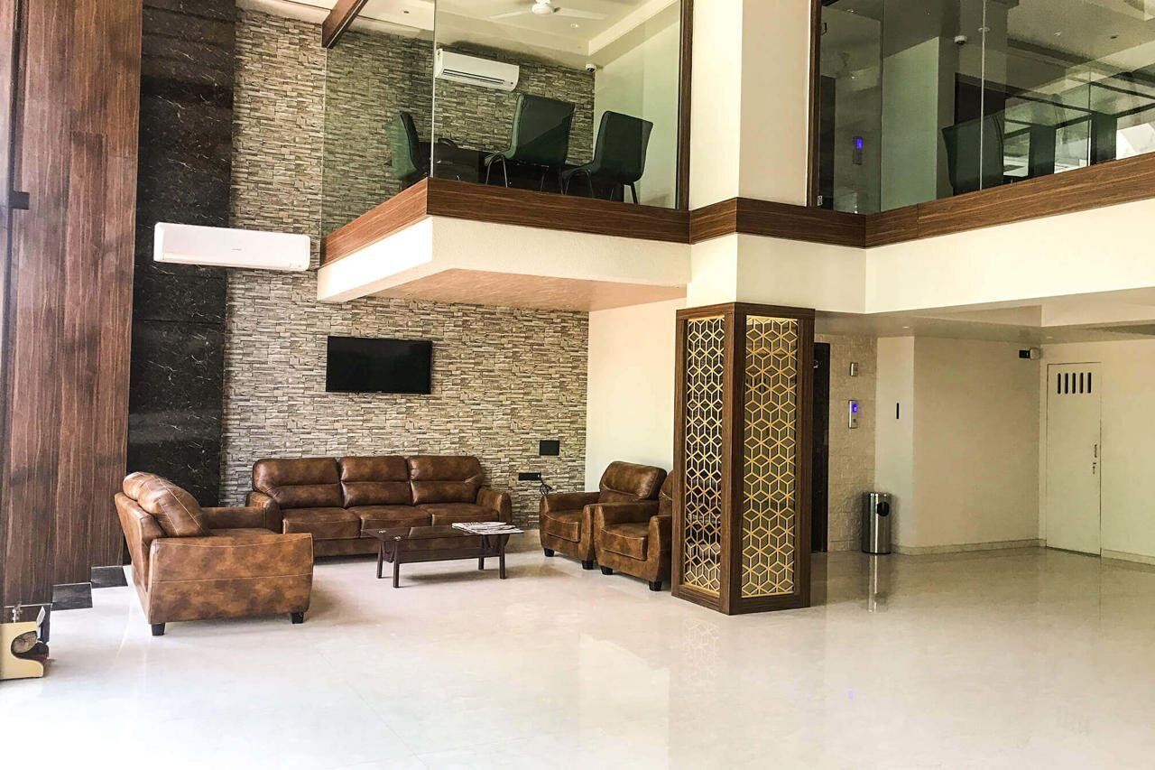 A spacious lobby with a high ceiling, a stone wall, and a seating area with leather sofas.