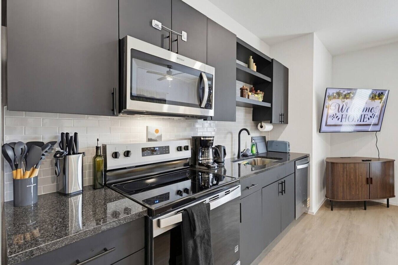 Een moderne keuken met een magnetron, kookplaat en koffiezetapparaat.