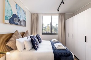 Une chambre d’hôtel avec un lit, une fenêtre, une armoire et un tableau au mur.