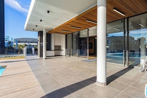 An outdoor area with a pool, glass doors, and a wooden ceiling. - Modern Luxury at Park Place by Ctha (Cape Town)