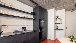 A modern kitchen with black cabinets, a built-in oven, and a red floor. - The Urban Nest by CTHA (Cape Town)