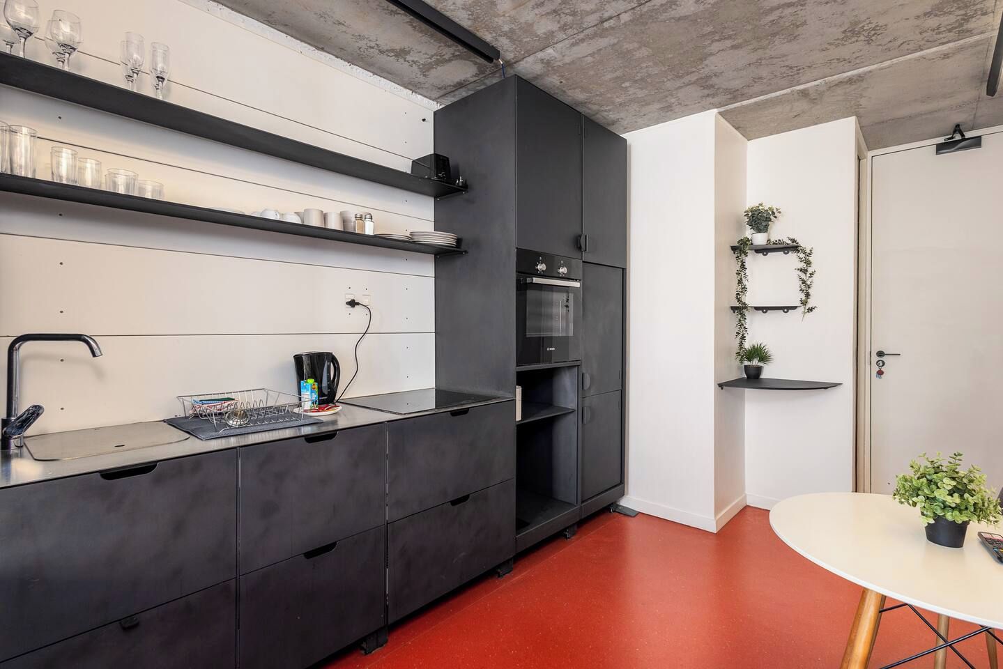 Une cuisine moderne équipée d’un four encastré, d’une machine à café et d’un coin repas avec une table et des chaises.