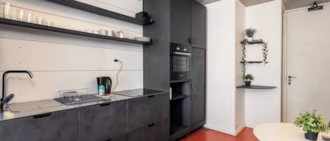 Une cuisine moderne équipée d’un four encastré, d’une machine à café et d’un coin repas avec une table et des chaises.