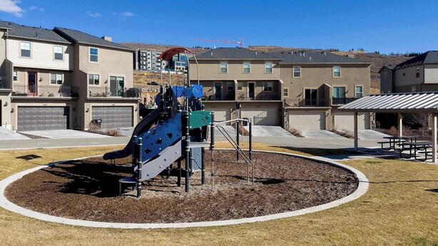 A playground with a slide and climbing structures, surrounded by a landscaped area with mulch, in a residential neighborhood with multi-story houses. - Ski Haven Hideaway 15 Mins to Park City Slopes (Hideout)