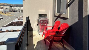 A balcony with a barbecue grill, red chairs, and a view of a street and buildings. - Ski Haven Hideaway 15 Mins to Park City Slopes (Hideout)