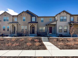 A row of townhouses with a front porch, a driveway, and a landscaped area with mulch and small shrubs. - Ski Haven Hideaway 15 Mins to Park City Slopes (Hideout)