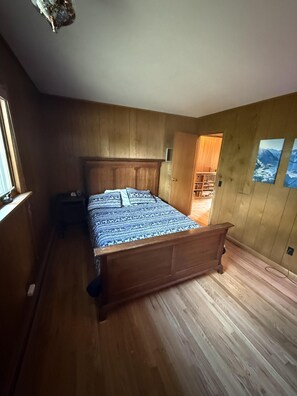 Una camera da letto con un letto in legno, un comodino e un armadio in legno.