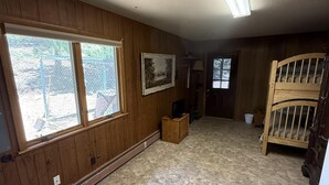 Una habitación con paneles de madera, un ventanal grande, un cuadro enmarcado y una cama.