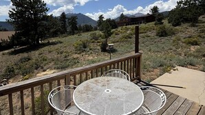 Una terraza con una mesa y sillas metálicas redondas, con vistas a un paisaje montañoso.
