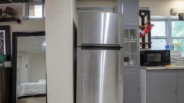 A compact kitchen with a stainless steel refrigerator, a microwave, and grey cabinets. - Near NYC & Metro-North! Private Yonkers Studio (Yonkers)