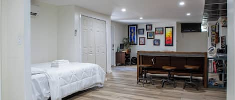 A bedroom with a bed, a desk, and a chair. There are framed pictures on the wall.