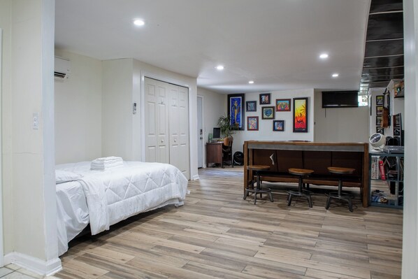 A bedroom with a bed, a desk, and a chair. There are framed pictures on the wall.