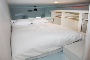 A bedroom with a bed, a ceiling fan, and built-in storage.